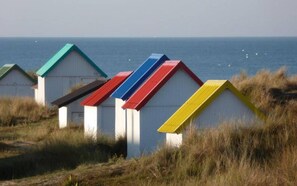 A row of beach huts with colorful roofs, set against a coastal backdrop. - Comfortable individual lodgings in a natural setting. (GOUVILLE-SUR-MER)