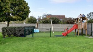 Un parque infantil con un tobogán rojo y una estructura de madera para escalar.