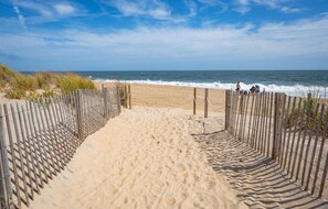 A sandy beach with a wooden fence leading to the ocean.