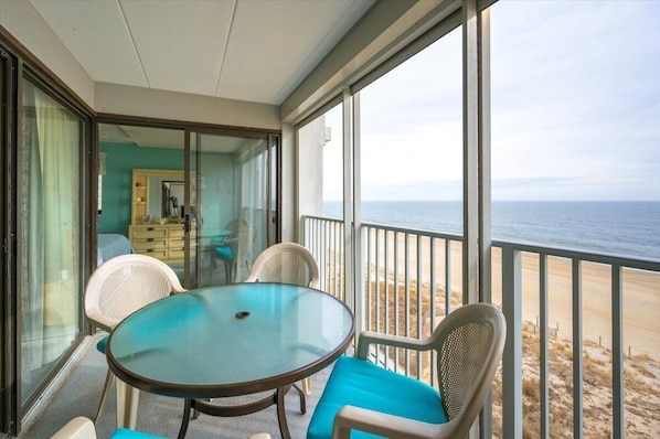 Enjoy the ocean view from this balcony with a glass table and comfortable seating.