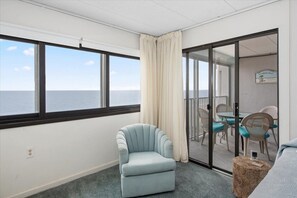 Enjoy ocean views from the comfort of your room, featuring a light blue armchair and an outdoor area with seating.