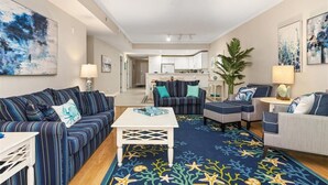 Un vaste espace de vie agrémenté de canapés à rayures, d’une table basse blanche et d’un tapis à motifs bleus.