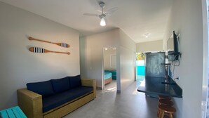 A modern living room with a sofa, a coffee table, and a TV mounted on the wall. - Chalés Céu e Mar (Ubatuba)