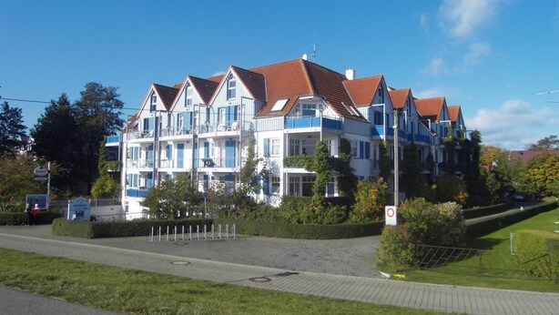 Een meerlaags hotel in traditionele stijl, met balkons en een rode dakbedekking.