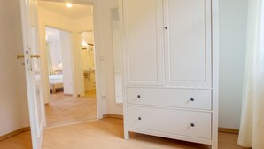 Een kamer met een witte kast, een bed en een badkamer, zichtbaar door een geopende deur.