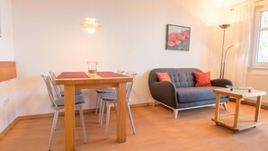 Een moderne woonkamer met een eettafel, een grijze bank en een kleine tafel met een spel.