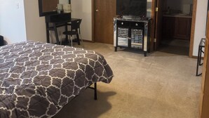 Une chambre à coucher comprenant un lit, un bureau, une télévision et une commode.