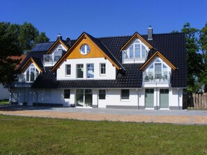 Ein modernes, zweistöckiges Haus mit Balkon, Garage und einem großen Fenster.