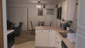 Una cocina compacta con zona de comedor, un refrigerador, un microondas y un lavamanos.