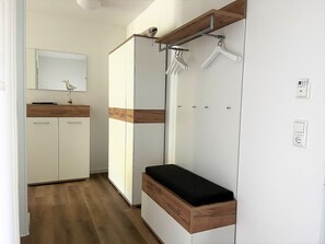Ein modernes Badezimmer mit einem Holzbadezimmerhocker, einem Spiegel und einer Duschkabine.
