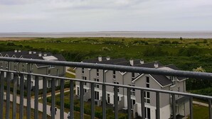 Ein Wohngebiet mit modernen Gebäuden, einer grünen Wiese und Blick aufs Meer.