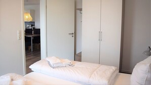 Ein Schlafzimmer mit Bett, Kleiderschrank und Schreibtisch mit Lampe.