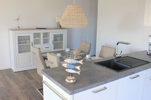 A modern kitchen with a grey countertop, white cabinetry, and a black sink.