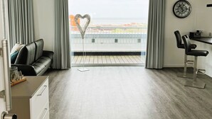 Ein modernes Hotelzimmer mit Balkon, einer Sitzecke, einem Schreibtisch und Blick auf die Stadt.