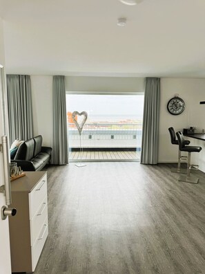 Une chambre d’hôtel moderne dotée d’un balcon, d’un canapé, d’un bureau et offrant une vue sur la ville.