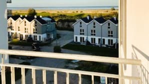 A residential area with multiple two-story houses, a clear view of the beach, and a balcony railing. - 49.4.M Ankerplatz - Modern, high-quality vacation apartment, sauna, large balcony, (Wangerland)