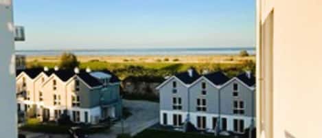 A residential area with multiple two-story houses, a clear view of the beach, and a balcony railing.