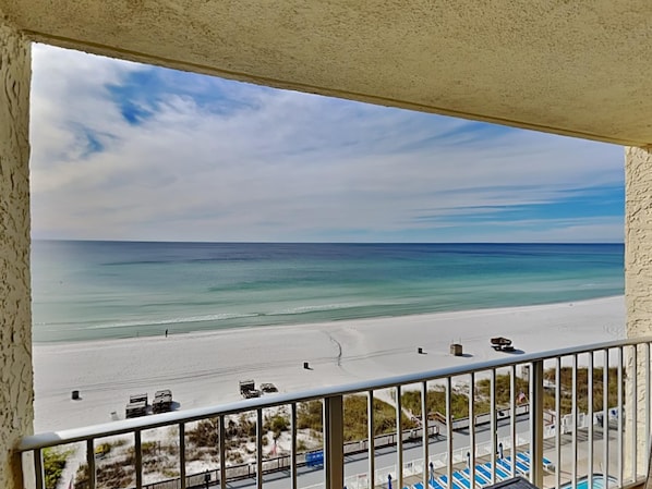 A balcony with a view of a beach and ocean.