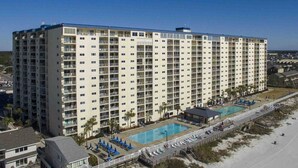 Ein mehrstöckiges Hotel mit Poolanlage, einschließlich eines großen Pools und eines kleineren Pools, sowie einer Strandlage.