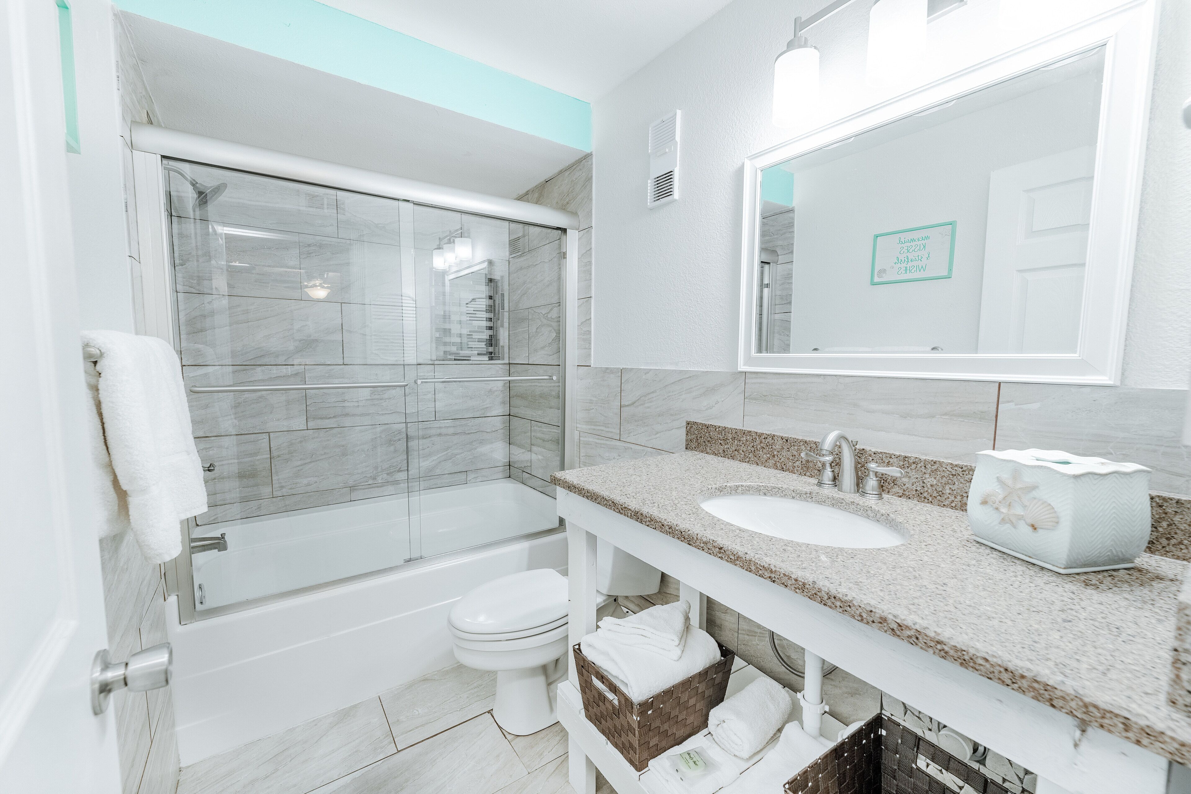 A modern bathroom with a glass shower enclosure, a bathtub, a toilet, and a vanity with a sink and mirror.