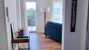 Un salon moderne avec un canapé bleu, une table basse en bois et une grande fenêtre.