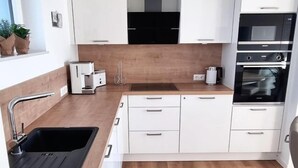 Une cuisine moderne avec des armoires blanches, un plan de travail en bois, un four encastré et un évier noir.