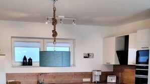 Une cuisine moderne avec une table à manger ronde, des meubles blancs et un four encastré.