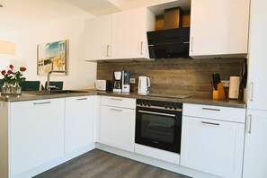 A modern kitchen with white cabinetry, a built-in oven, a coffee maker, and a microwave.