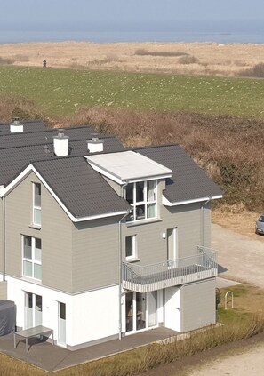 Een gebouw met twee verdiepingen, een plat dak, een balkon en een overdekt terras.