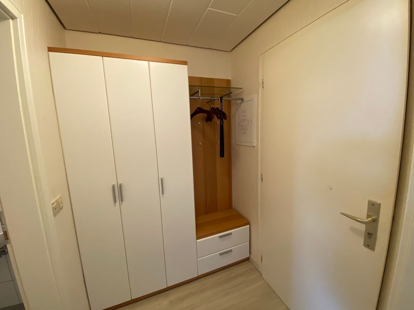 A walk-in closet with a wooden bench, a hanging rack, and a small drawer.