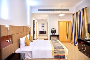 A hotel room with a large bed, a bedside table, a mirror, a wardrobe, and a television. - City Stay Grand Hotel Apartments (Dubai)