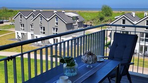 A balcony with a table, chair, and a view of a residential area and the sea. - 47.3.M Seestern - Well-kept apartment with sea view, infrared cabin, large balcony (Wangerland)