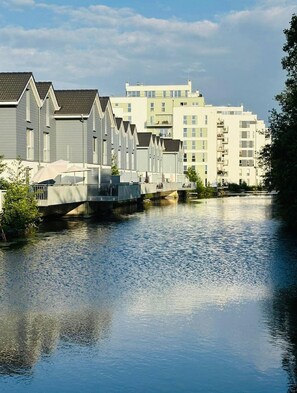 Un canal bordé de maisons mitoyennes, avec un immeuble à plusieurs étages en arrière-plan.