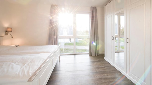 Un dormitorio con una cama grande, un armario y una ventana con cortinas.