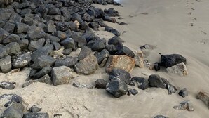 Ein Strand mit einem Felssturm und einer Sandküste, sowie Wellen im Meer.