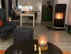 Olohuone, jossa on sohva, pieni sohvapöytä, jossa on kynttilä, ja takka.