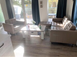 A modern living room with a sofa, armchair, and a coffee table. - 47.1.S Waterkant - Cozy, well-kept vacation apartment near the beach, own (Wangerland)
