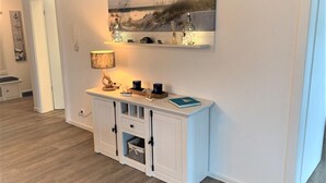 Uma sala de estar moderna com uma mesa de console branca, uma luminária e um quadro acima.