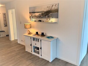 Ein modernes Wohnzimmer mit einem weißen Konsolentisch, einer Lampe und einem Gemälde darüber.