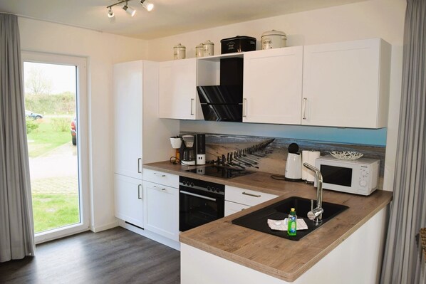 Fridge, microwave, oven, stovetop - House No. 40, Ferienhaus Deichgraf - Modern vacation home, sauna, south-facing terrace, (Wangerland)