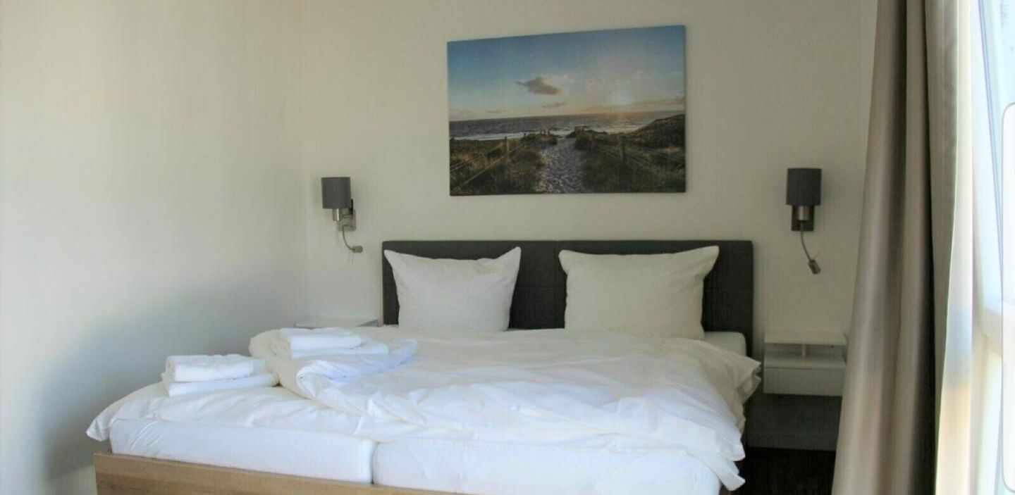 Una cama bien hecha con sábanas blancas en una habitación de hotel.