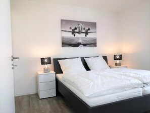 Ein Schlafzimmer mit einem Bett, zwei Nachttischen, einer Kommode und einem Wandbild.