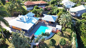 An aerial view of a residential area with a swimming pool, houses, and lush greenery.