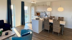 Una cocina moderna con armarios blancos, una isla central e iluminación colgante.