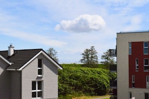 Ein Wohngebiet mit einem Haus mit geneigtem Dach und Schornstein, angrenzend an ein rotbacksteins Gebäude mit zahlreichen Fenstern.