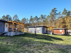 Un terrain de camping comprenant plusieurs cabanes en bois, un espace de pique-nique couvert et un petit abri.