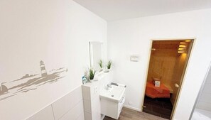 A bathroom with a sink, mirror, and a wall decal of a lighthouse.
