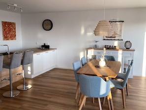 Cozinha moderna com armários brancos, bancada de madeira e um relógio na parede.