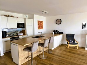 A modern kitchen with white cabinets, a wooden island, and bar stools.