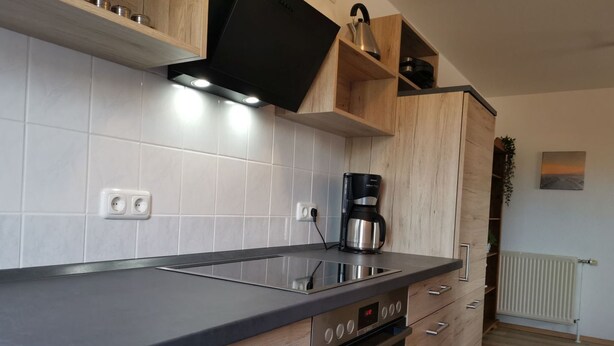 A modern kitchen with a built-in oven, a coffee maker, and wooden cabinets. - Domicil - Evening sun - "Domicil" Enjoy the evening sun! (Dahme)
